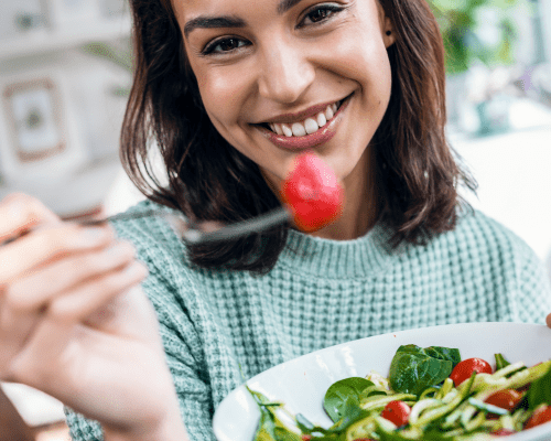 A Woman Holding a Fork and Eating a Bowl of Salad