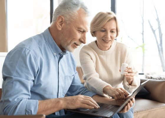 An elderly couple looking at the screen of a laptop